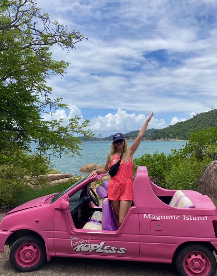 girl standing in a pink roofless car