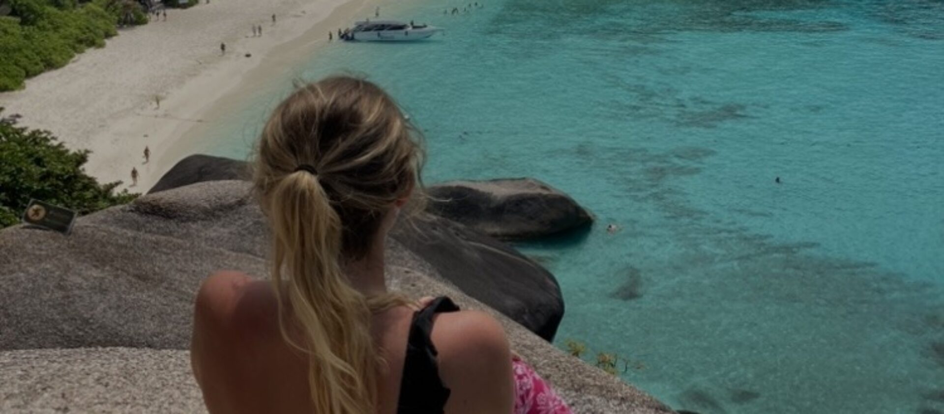 girl with blonde ponytail looking out at blue sea