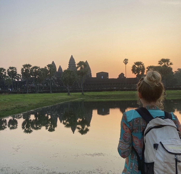 girl watching sunrise over ancient temple