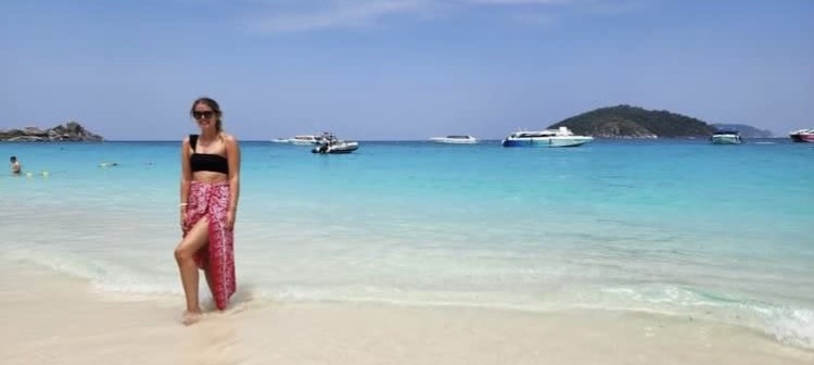 girl in pink skirt standing in bright blue sea