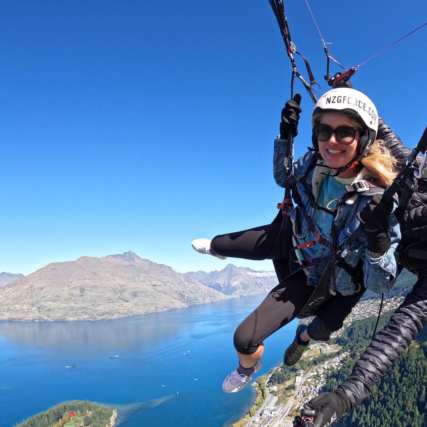 girl paragliding over water and trees