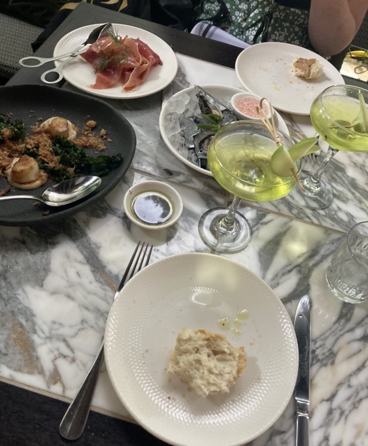 assortment of dishes on restaurant table with green cocktails in foreground