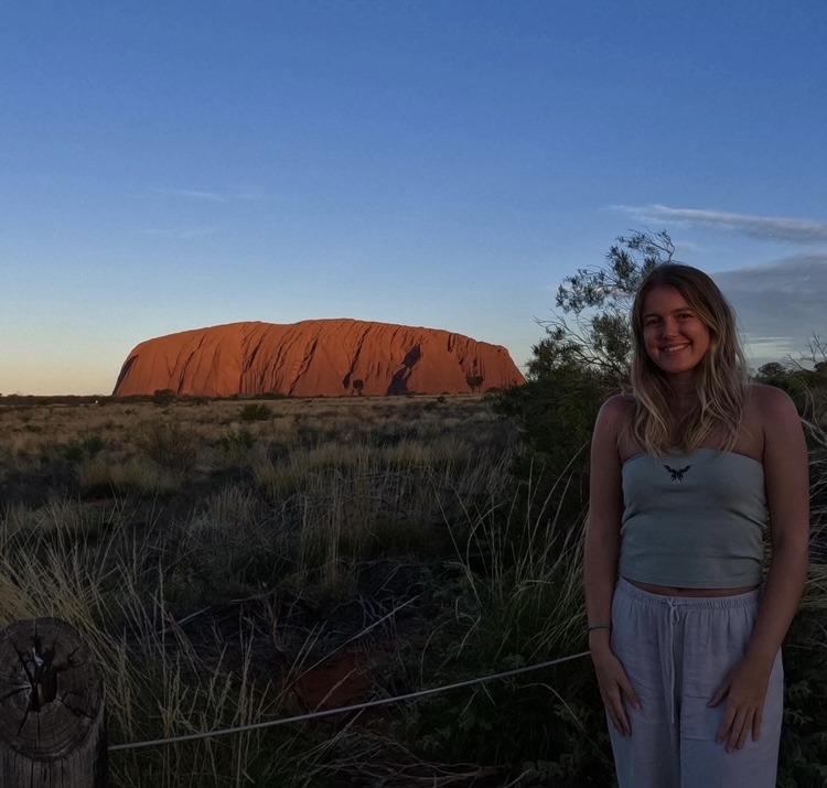 girl standing in front of big red rock