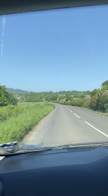 view from car windscreen of road and green fields